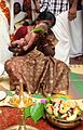 Image 16A new born's Namakarana ceremony. The grandmother is whispering the name into the baby's ear, while friends and family watch. (from Samskara (rite of passage))