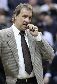 Flip Saunders, en costume, mordant dans un crayon qu'il tient de la main gauche.