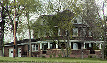 A two-story gabled house with a wraparound porch