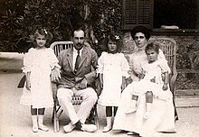 Photographie en noir et blanc montrant un couple assis avec trois filles vêtues de blanc.