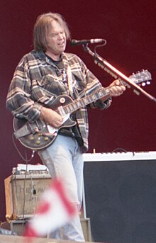 A gray-haired man playing a guitar