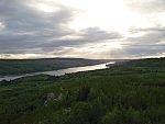 Sunset over a river winding through thick evergreen forests.