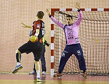 Photo d'un gardien de handball subissant un tir.