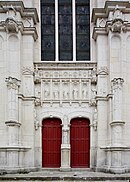 Vue de la façade d'une église, de son portail à deux battants et de la verrière qui le surmonte.