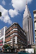 In the foreground: the abandoned Yoyogi Kaikan [ja] building that appears in the film. The demolition of the building was completed in January 2020 and it no longer exists.[140] Note that the rooftop shrine in this film is fictional. Back: the NTT DoCoMo Yoyogi Building (Docomo Tower), which frequently appears in Shinkai's films.