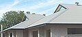 Applying corrugated iron sheeting to a house under construction. Shows two gables and external cyclonic fastenings