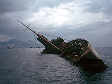 A half-sunken ship lies listing at 45 degrees