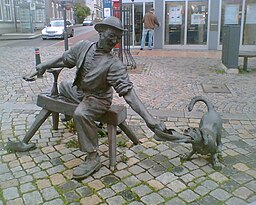 Staty på stadens centrala torg som framställer en skomakare.