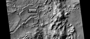 Low, layered mesa, as seen by HiRISE under HiWish program. Arrows point to some layers.