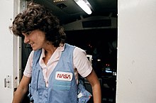 Ride standing in a doorway in a NASA uniform