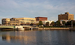 Manitowoc River, near where it enters Lake Michigan, reflecting the skyline of downtown Manitowoc, with the U.S. 10 highway bridge at left