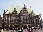 A dark stone gothic building in a paved town square.