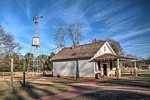 A rural storehouse with a small windmill next to it