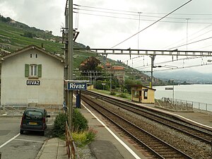 Two-story station building next to double-track railway line