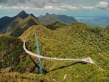 Pont suspendu au-dessus de petites collines typiques de l'Asie du Sud-Est.