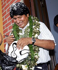 Evo Morales segurando uma bola de futebol e autografando-a