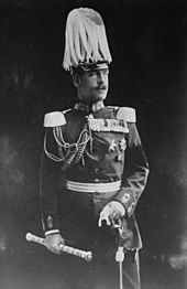 photographie noir et blanc : un homme moustachu en grand uniforme avec un casque à plumets