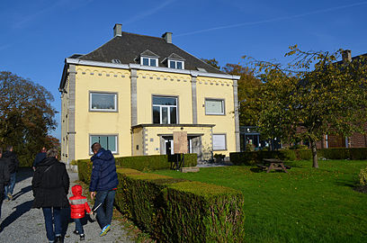 Immeuble ressemblant à une villa quatre façades peinte en jaune dans un parc.