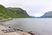 Un lac entouré de montagnes séparées par une vallée en U