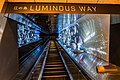 An escalator illuminated with space-themed lighting in the background.