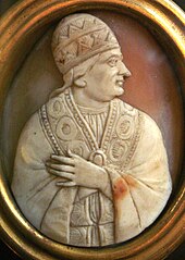 Cameo of the upper body of an older jowled man looking to the side. He is wearing papal vestments and a conical skull cap, while his left hand is holding the robe closed.