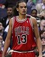 A basketball player, wearing a red jersey with the word "BULLS" and the number 13 on the front, is standing on a basketball court.