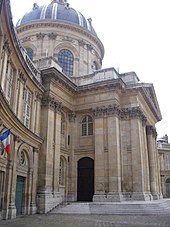 Bâtiment vu en partie avec en enfilade une aile et une entrée monumentale surmontés d'un dôme.