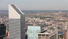 The slanted top of 601 Lexington Avenue, in the left foreground, as seen from Rockefeller Center. Other nearby skyscrapers are visible in the right foreground, while the borough of Queens is visible in the distance.