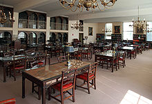 A room filled with many tables and chairs and bookshelves lining the walls.