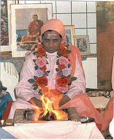 Swami Omkarananda sitzt im Schneidersitz vor einem vedischen Feuer im Jahr 1982