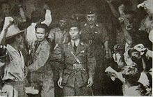 A man descending from a train in the midst of a crowd of reporters