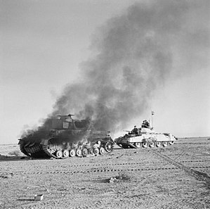 En britisk Crusader-kampvogn passerer en brændende tysk Panzer IV-kampvogn under operation Crusader. 27. november 1941