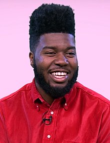 Picture of a young man smiling at the camera whilst sporting a red top