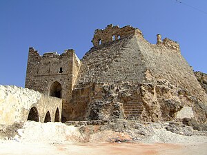 A photograph of a ruined castle on top of a hill. A river runs below it.