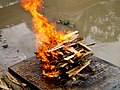 Image 3A Hindu cremation rite in Nepal. The samskara above shows the body wrapped in saffron on a pyre. (from Samskara (rite of passage))