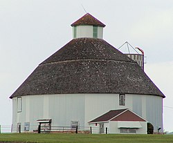 A large round barn with a gambrel roof and cupola