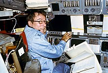 Photograph of Young sitting in the commander's seat on the Columbia flight deck