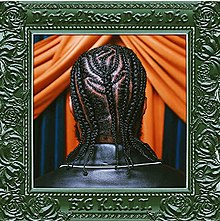 A photo of a Black man's head showing his braided hair. He's stood in front of blue and orange curtains, and the photo is surrounded by an ornate green photo frame.